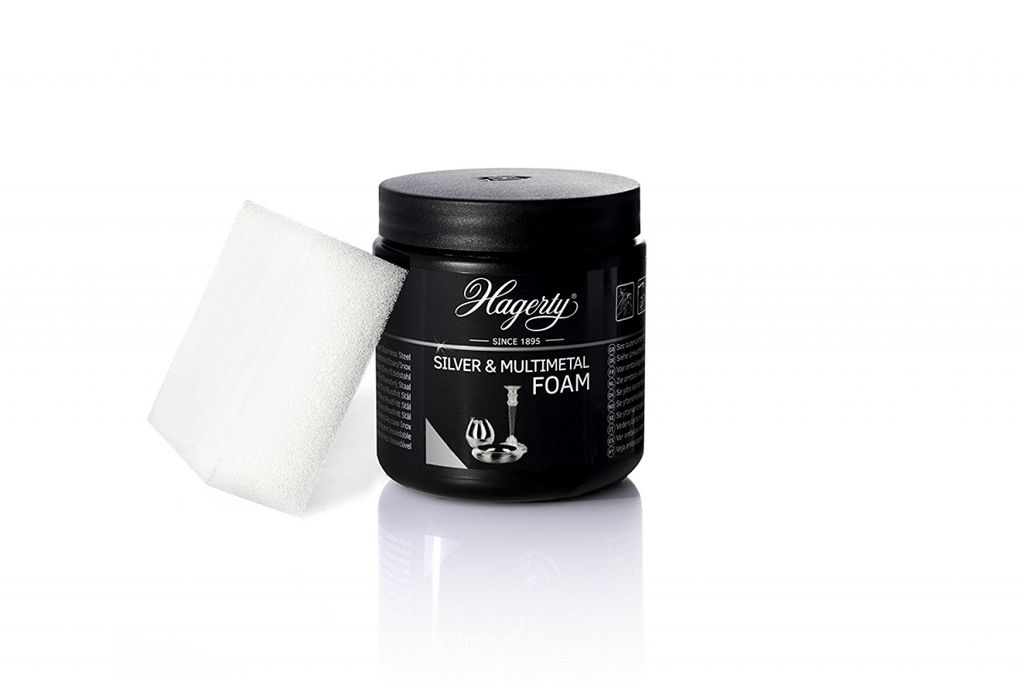 A black jar of Hagerty Silver & Multimetal Foam cleaner with a white sponge next to it, presented on a white background.