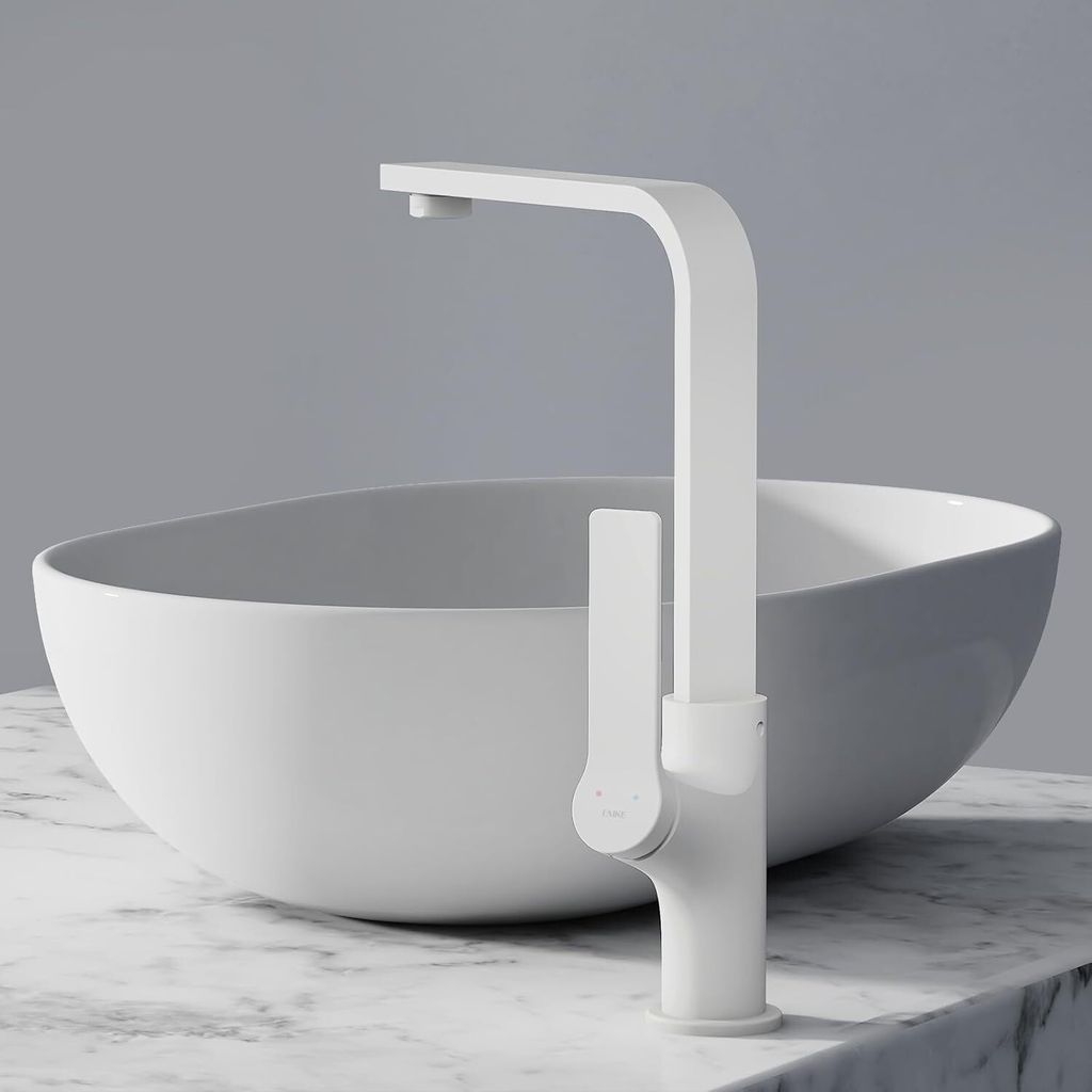 A white matte faucet is shown in front of a white basin, both resting on a marble countertop.