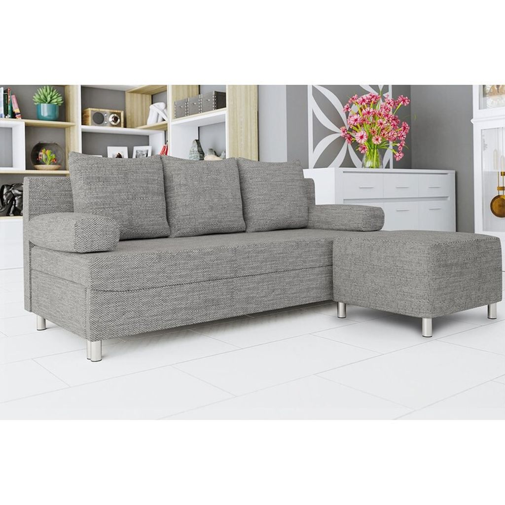 A gray sofa with an ottoman is shown in a room with shelves and a dresser in the background.