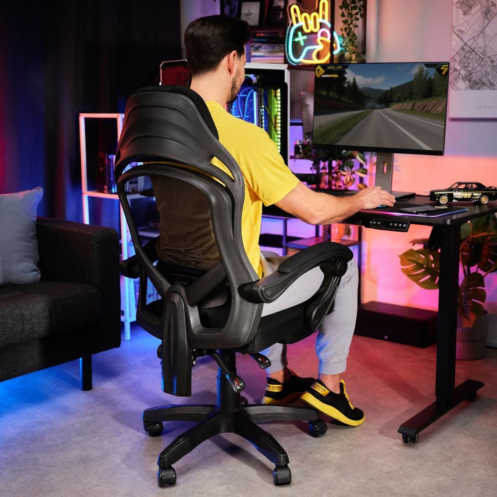 A man is playing a video game in a room with colorful lighting.