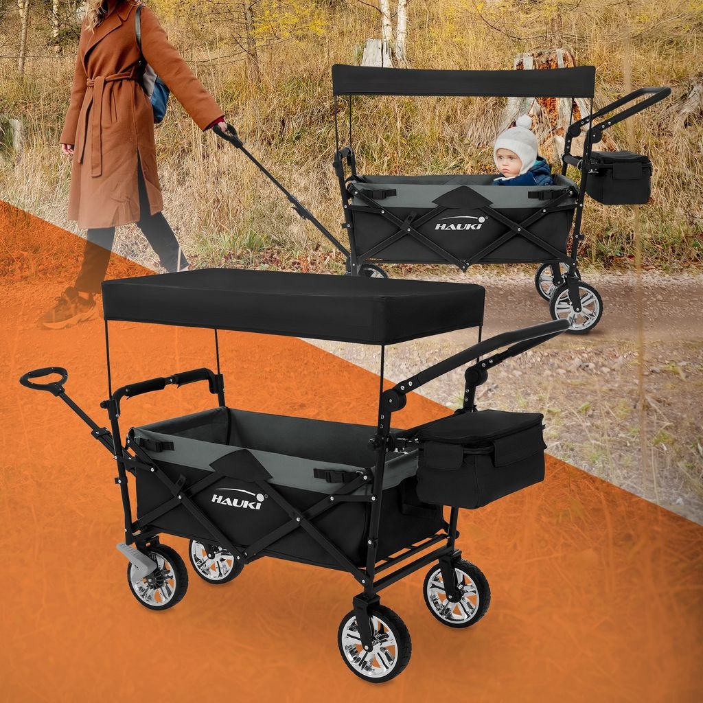 A woman is pulling a wagon with a baby in it on a path in a wooded area.