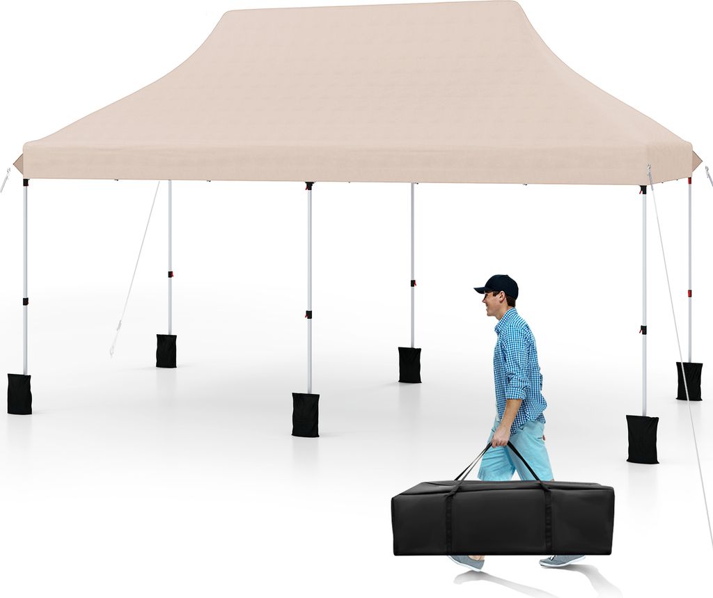 A man is walking with a black carrying bag in front of a beige pop-up tent.