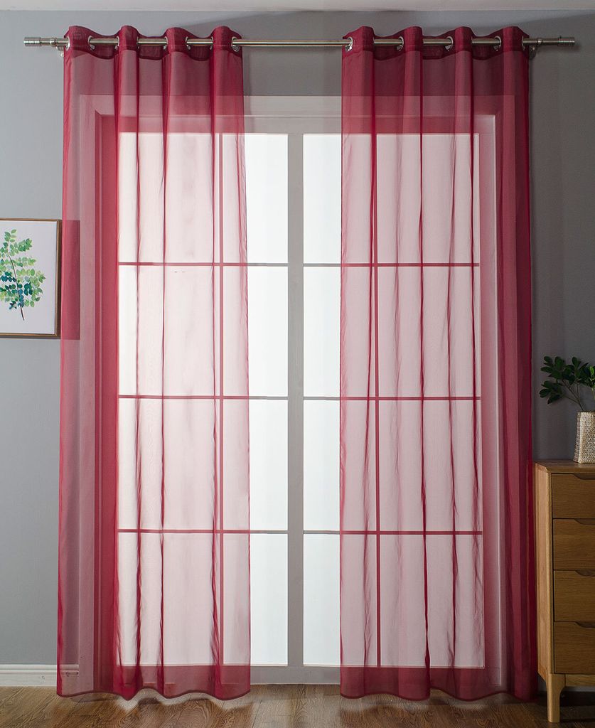 A room with a window covered by sheer red curtains.