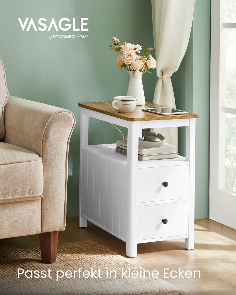 A VASAGLE side table with two drawers and a wooden top is placed next to a beige armchair in a room with a green wall and a window with sheer curtains.