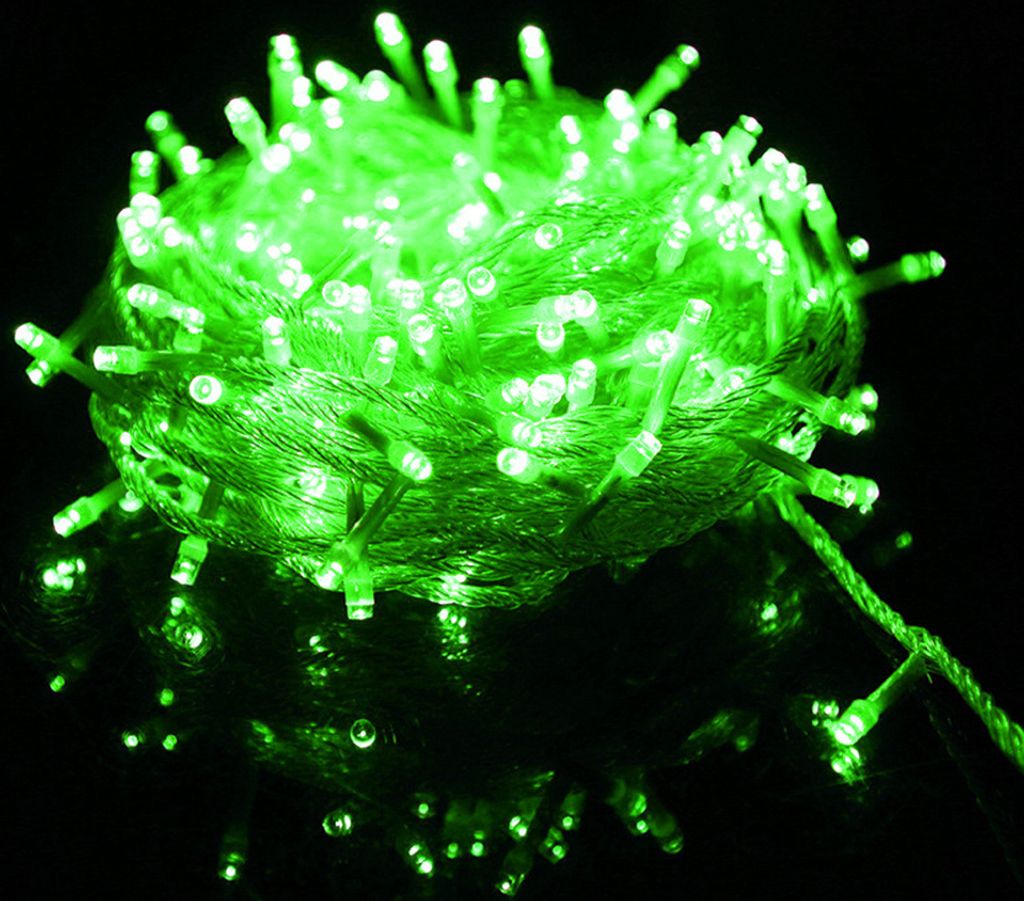 A close-up shot of a tangled ball of green LED string lights on a reflective black surface.