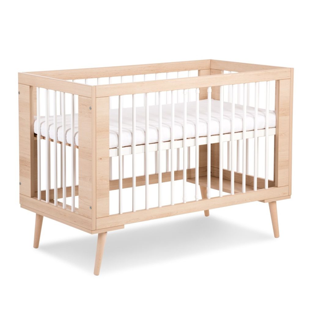 A wooden crib with white bars and a white mattress is shown against a white background.