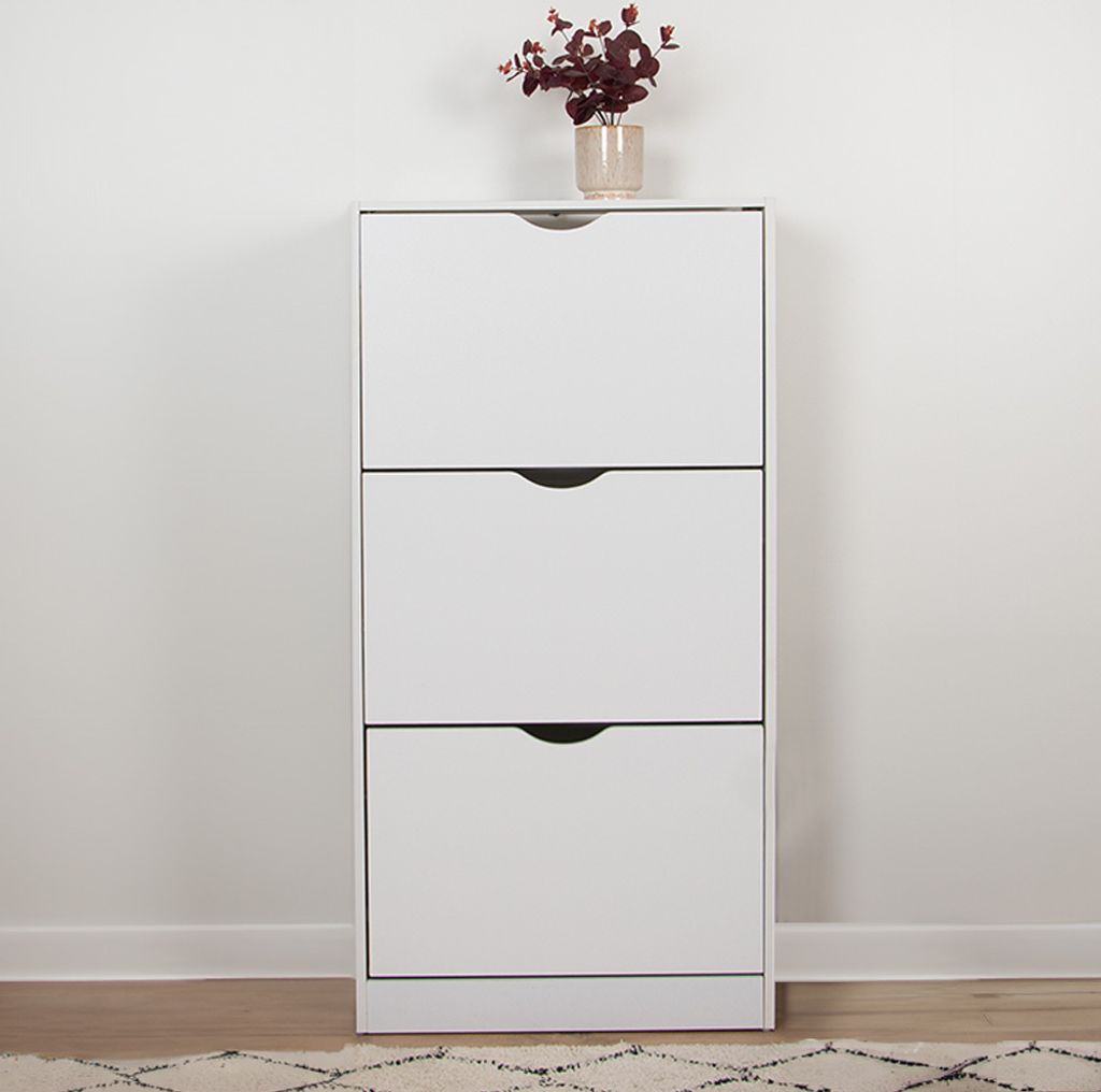 A white shoe cabinet with three drawers is shown against a white wall.