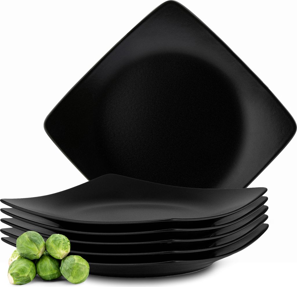 A stack of black square plates with a few Brussels sprouts in the foreground.