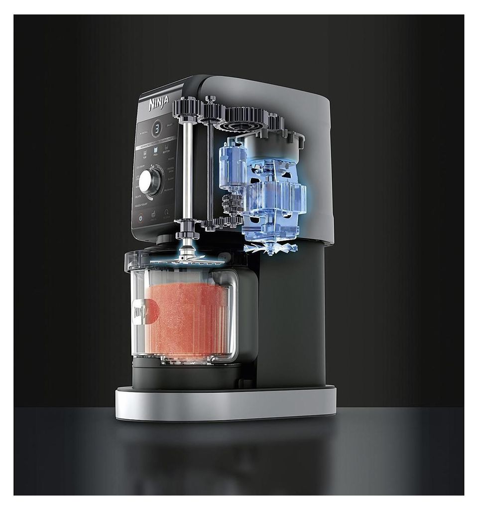 A cutaway view of a Ninja Creami ice cream maker, showing its internal mechanisms and a container filled with a pink mixture.