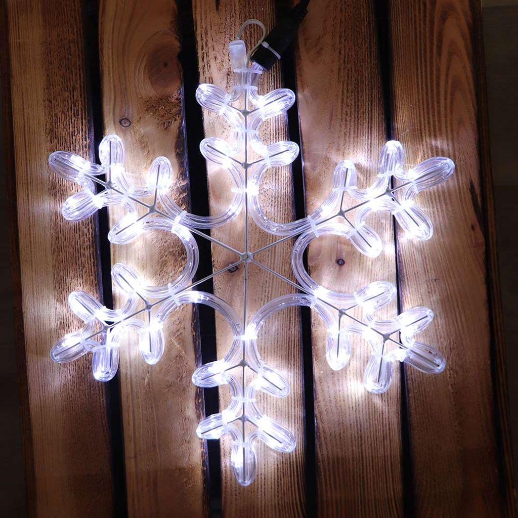 A lit snowflake decoration is placed on a wooden surface.
