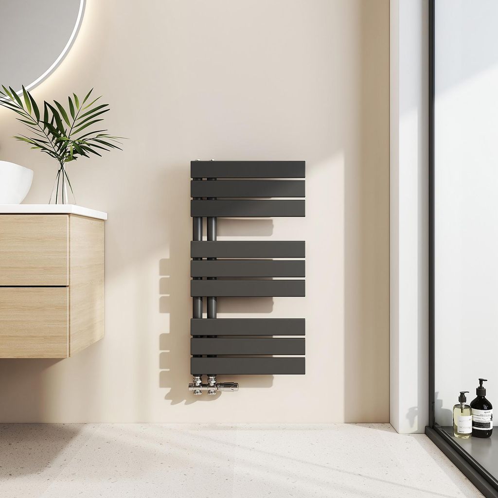 A modern bathroom setting with a sleek black towel radiator mounted on a cream-colored wall.