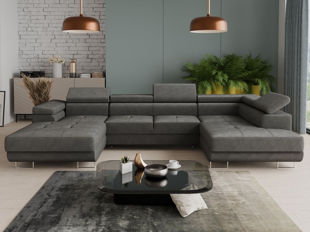 A modern living room with a large grey sectional sofa, a coffee table, and plants.