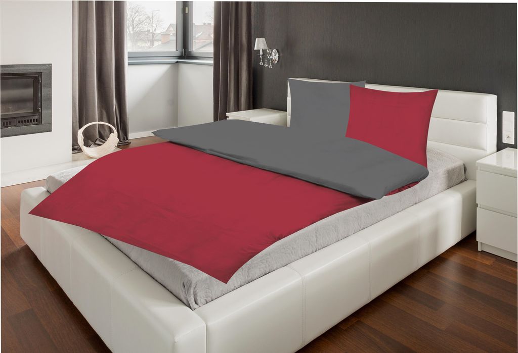 A bed with red and gray bedding in a bedroom.