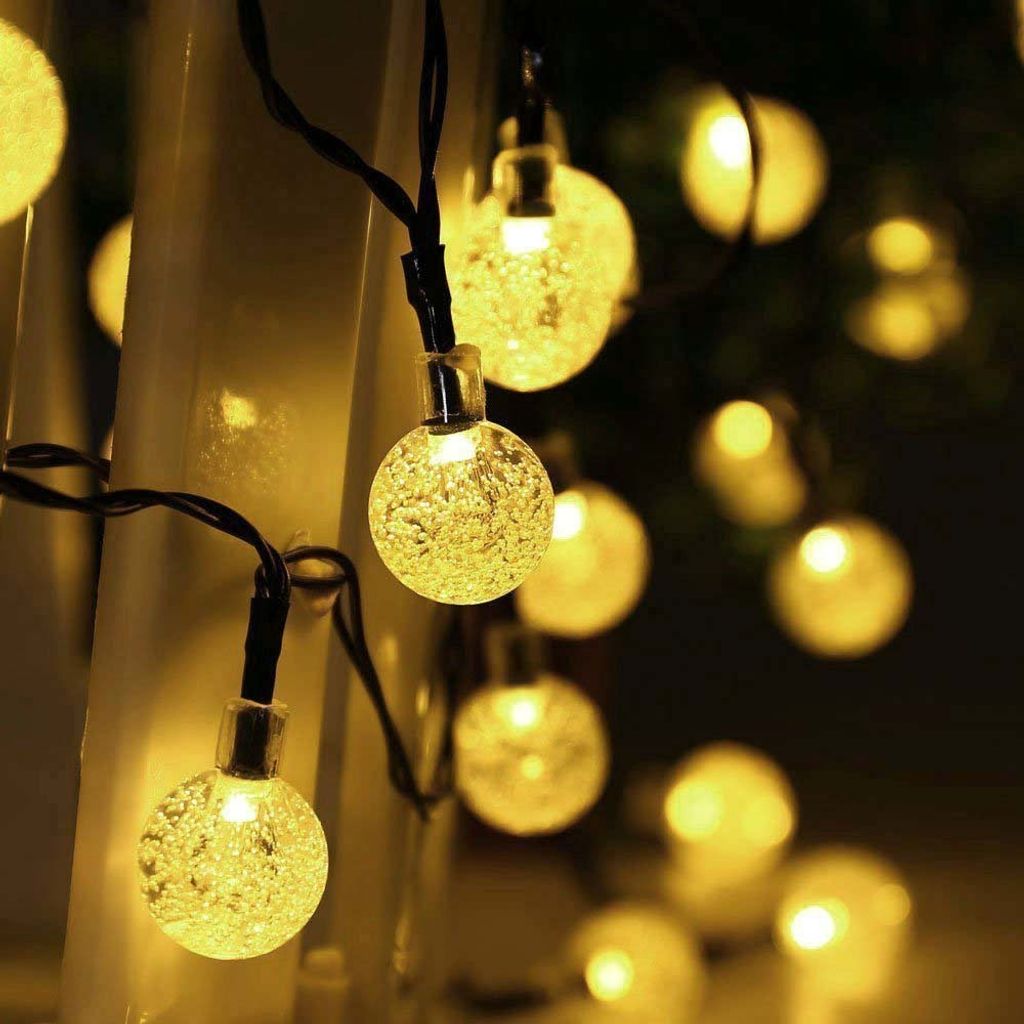 A close-up view of string lights with round, textured bulbs emitting a warm yellow glow.