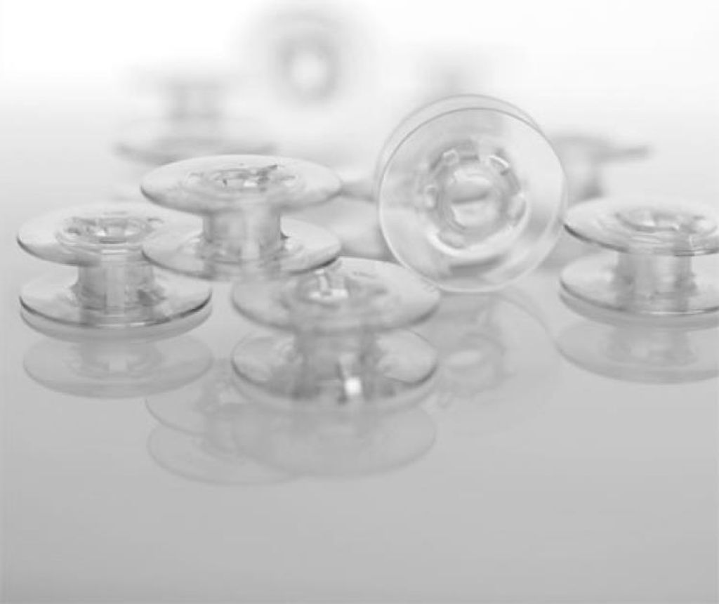 A collection of clear glass bobbins on a reflective surface.