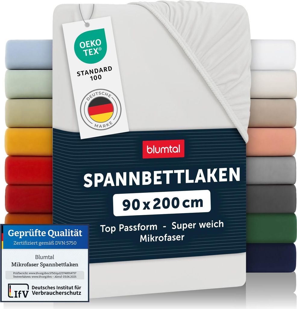 A stack of folded fitted sheets in various colors, with a white fitted sheet prominently displayed in the foreground, featuring product information tags.