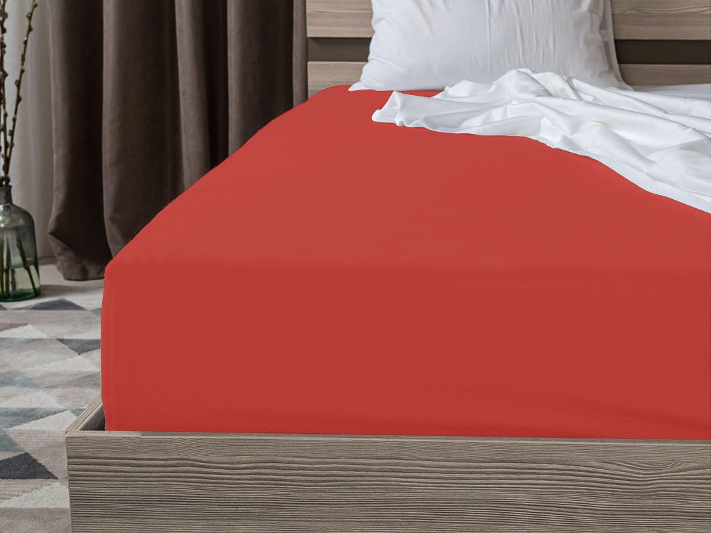 A close-up view of a red fitted sheet on a bed.