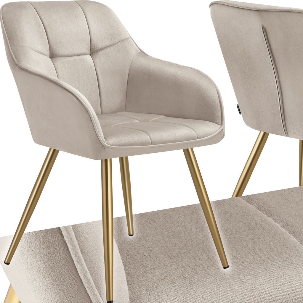 A close-up studio shot of a beige upholstered dining chair with gold legs.