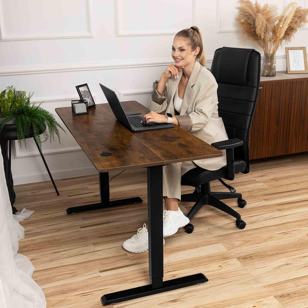 A woman is working at a standing desk in a home office setting.