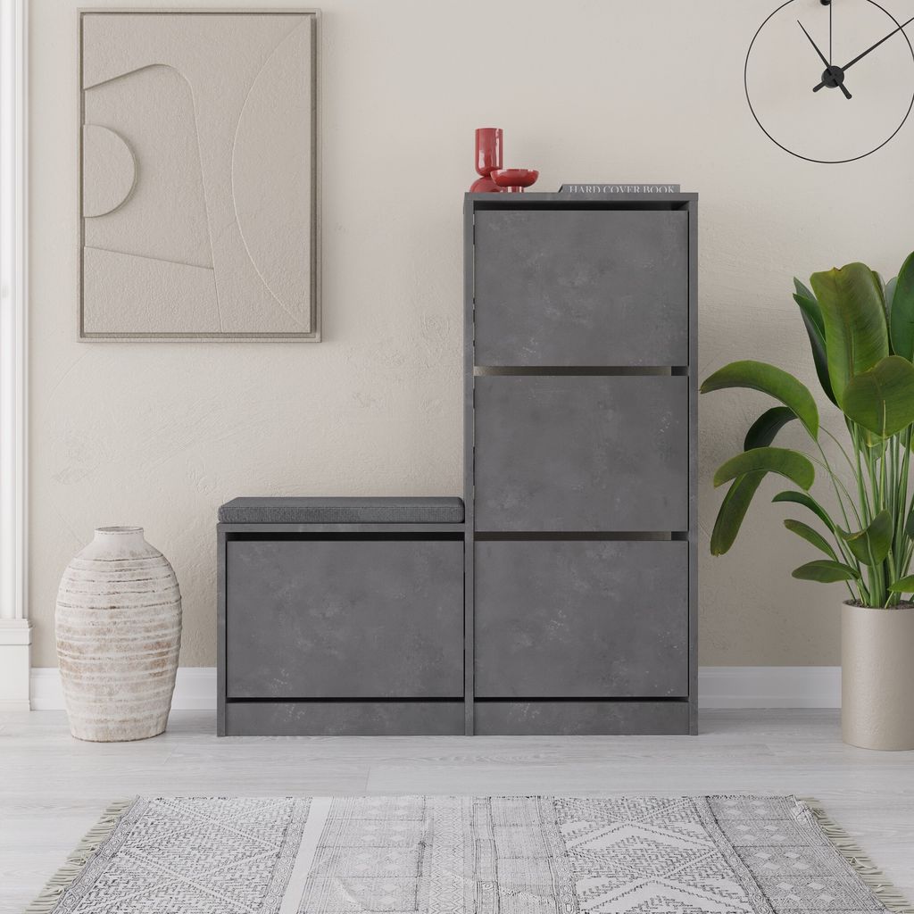 A modern entryway with a shoe cabinet and bench, a large vase, and a piece of abstract art.