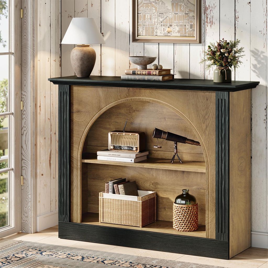 A console table with arched shelving, decorated with various items, in a room with wooden paneled walls and a window.