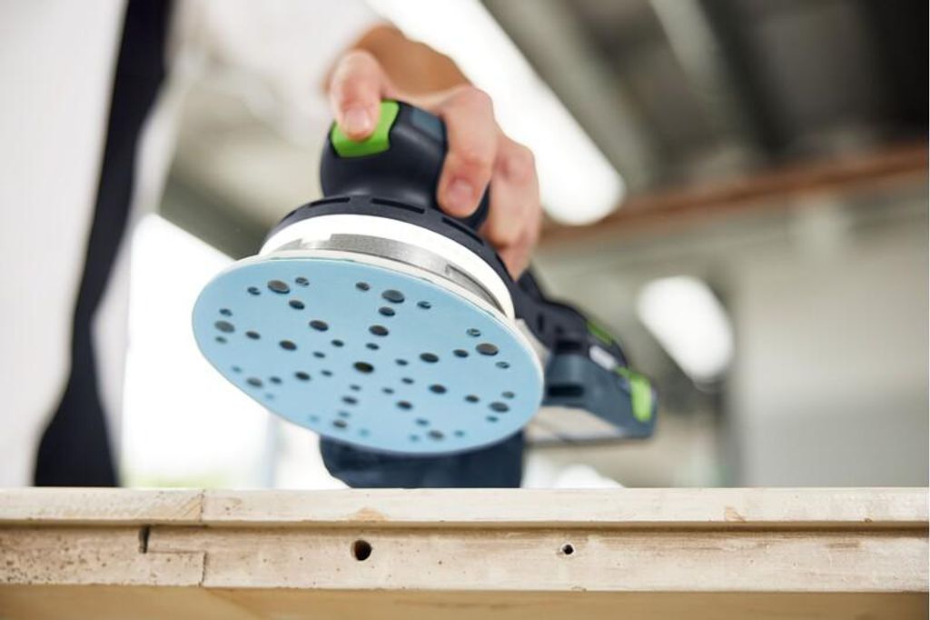 A person is using a sander on a wooden surface.