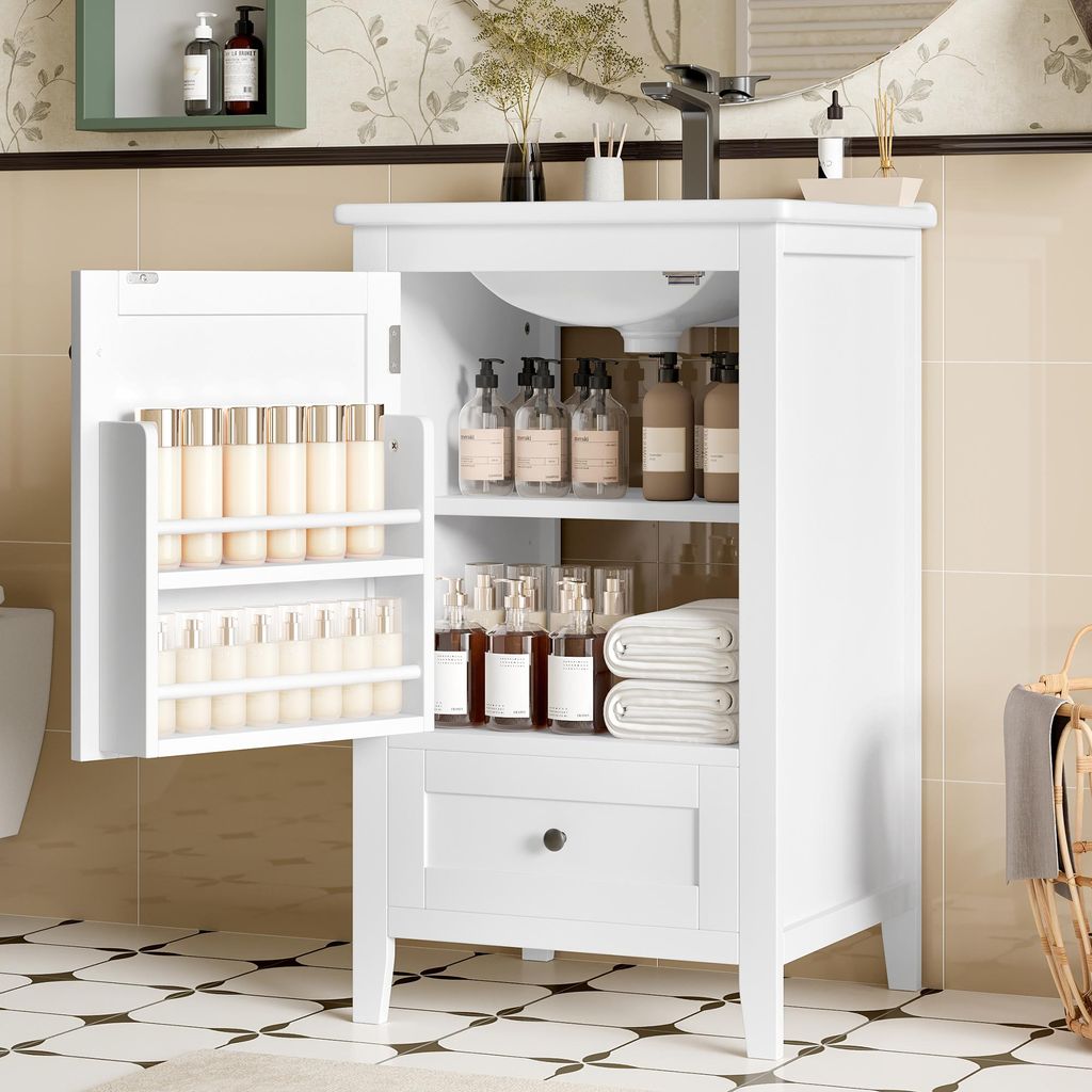 A white bathroom vanity cabinet with its door open, revealing shelves stocked with various bottles and towels. The cabinet has a drawer with a black knob. The background shows a tiled wall and floor, and a sink with a faucet.