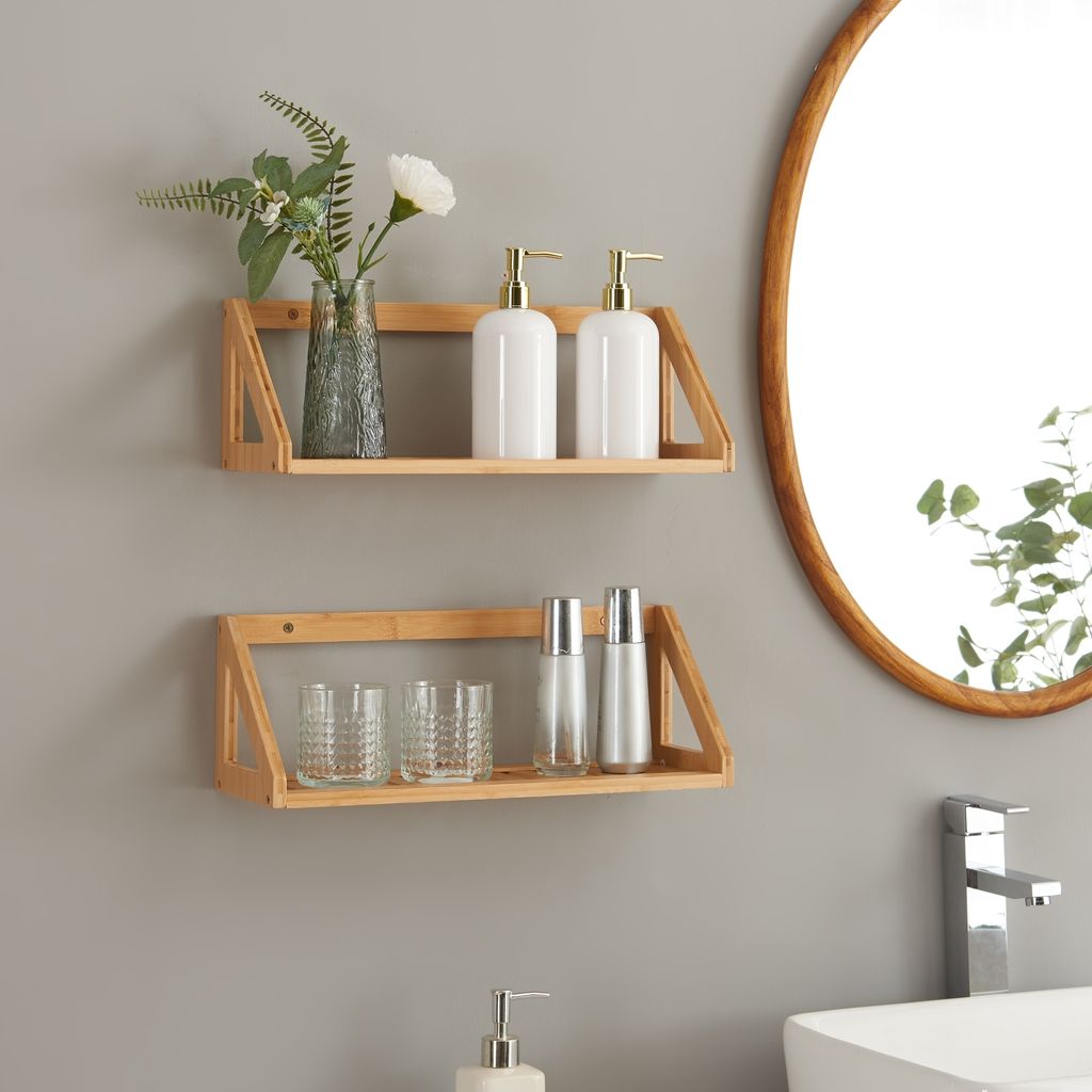 Two wooden shelves mounted on a gray wall, holding bathroom accessories and decorative items.