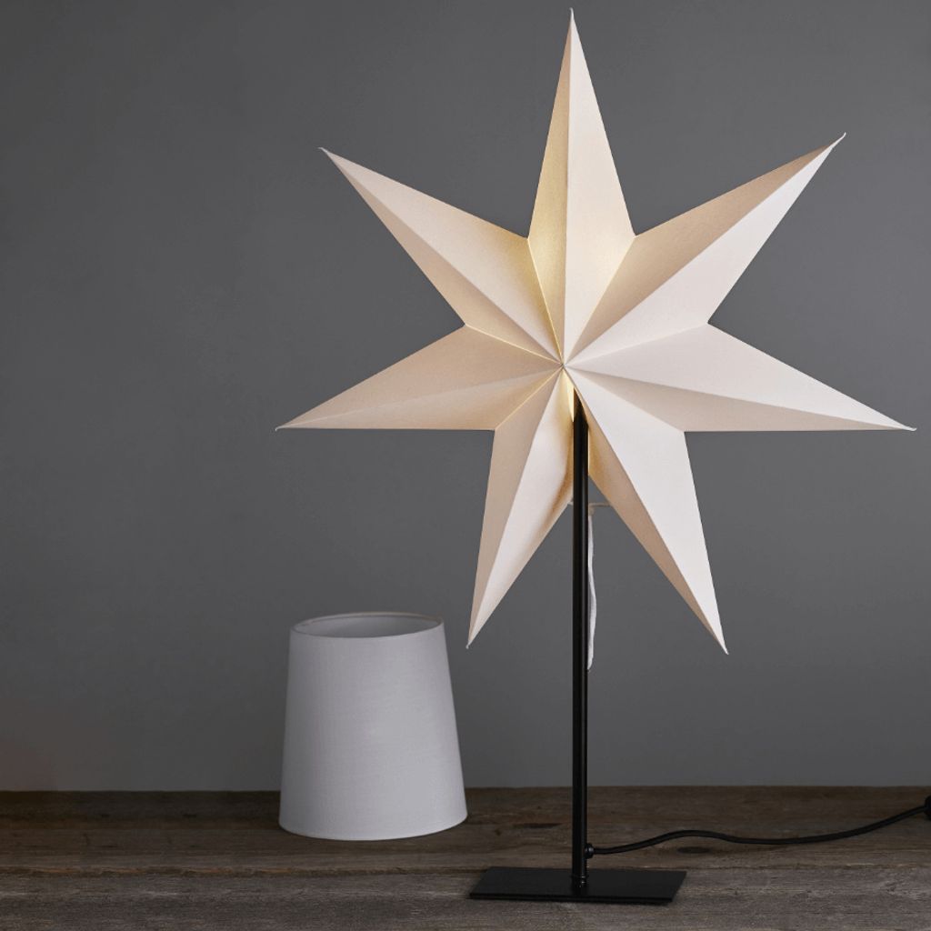 A white star-shaped lamp and a white lampshade on a wooden surface against a gray background.
