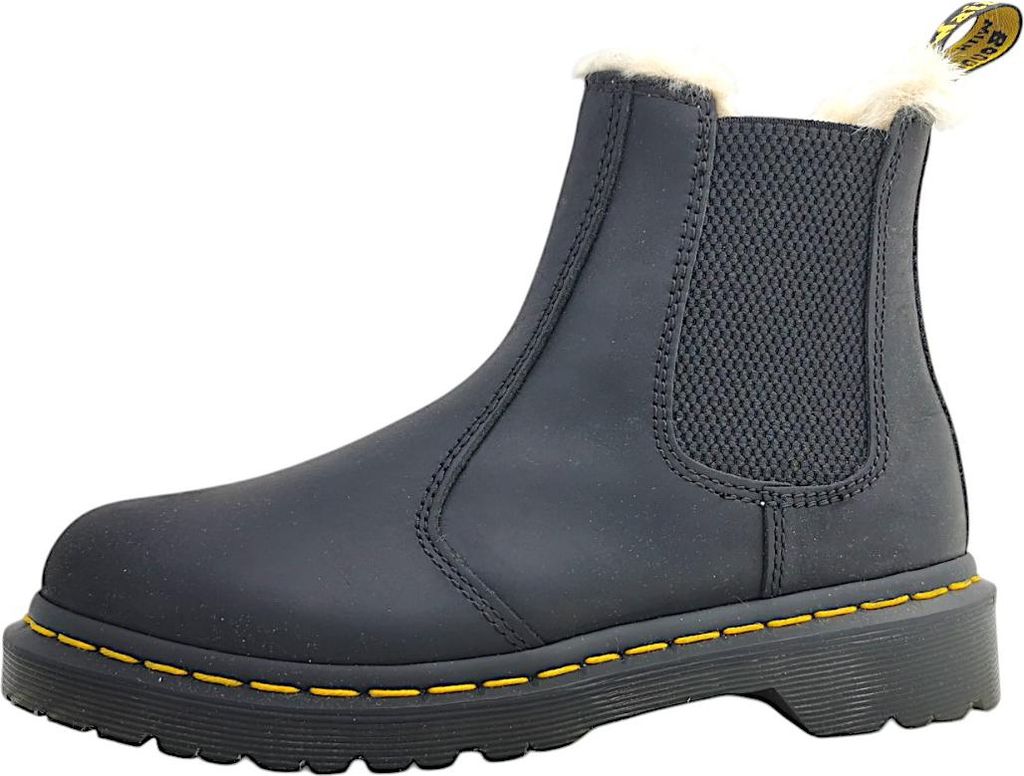 A single black Dr. Martens boot with yellow stitching and cream-colored fur lining is shown against a white background.