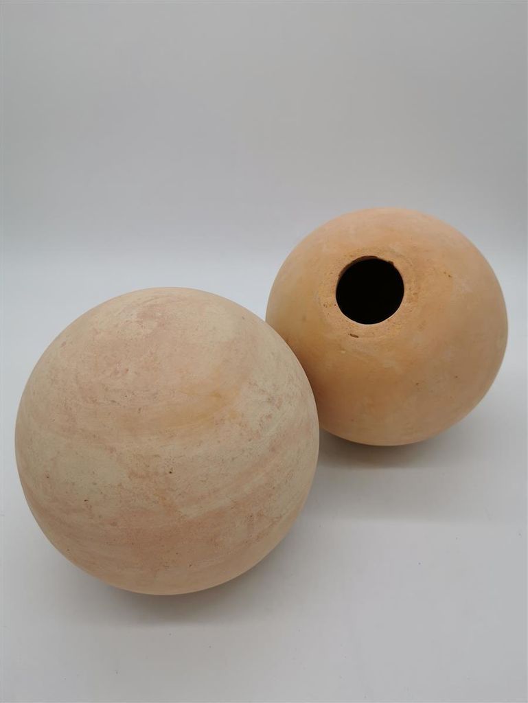 Two terracotta garden spheres on a white background.