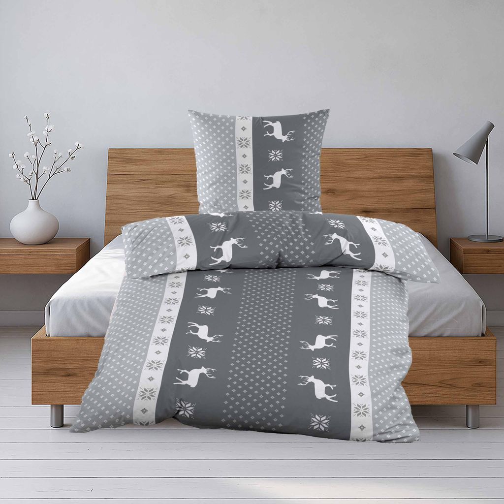 A bed with grey bedding featuring a reindeer pattern, set against a wooden headboard.
