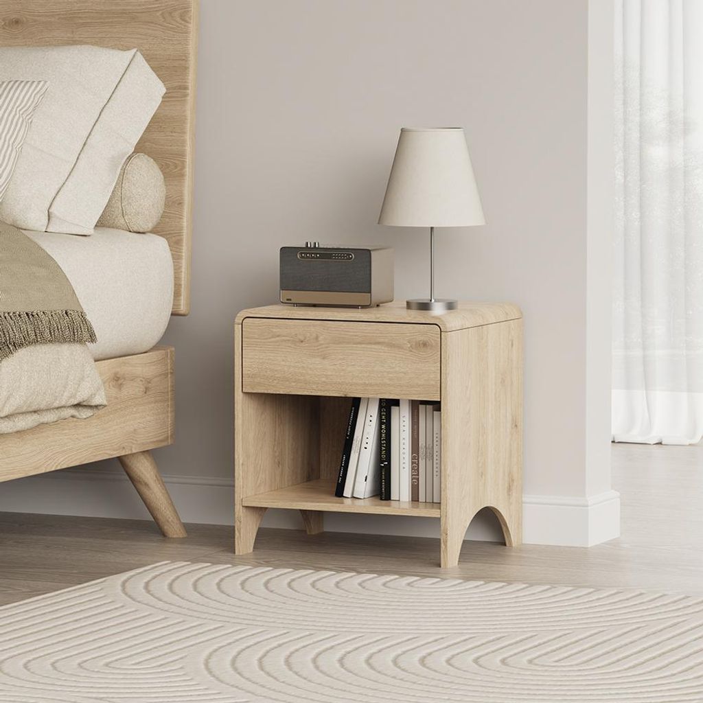 A bedroom scene with a nightstand next to a bed, featuring a lamp, radio, and books.