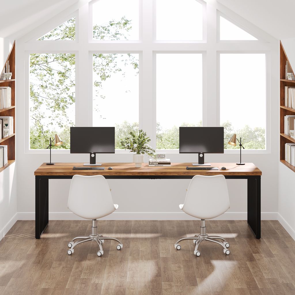 A modern home office setup with a large wooden desk and two computers, positioned in front of a large window.