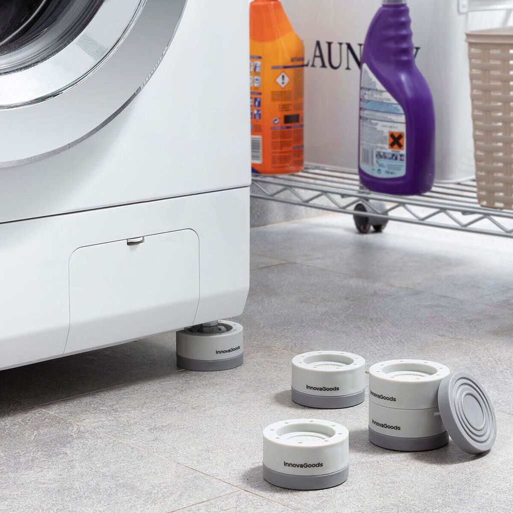 A washing machine is shown with anti-vibration feet installed, and extra feet are placed on the floor nearby. Cleaning supplies are visible on a shelf in the background.
