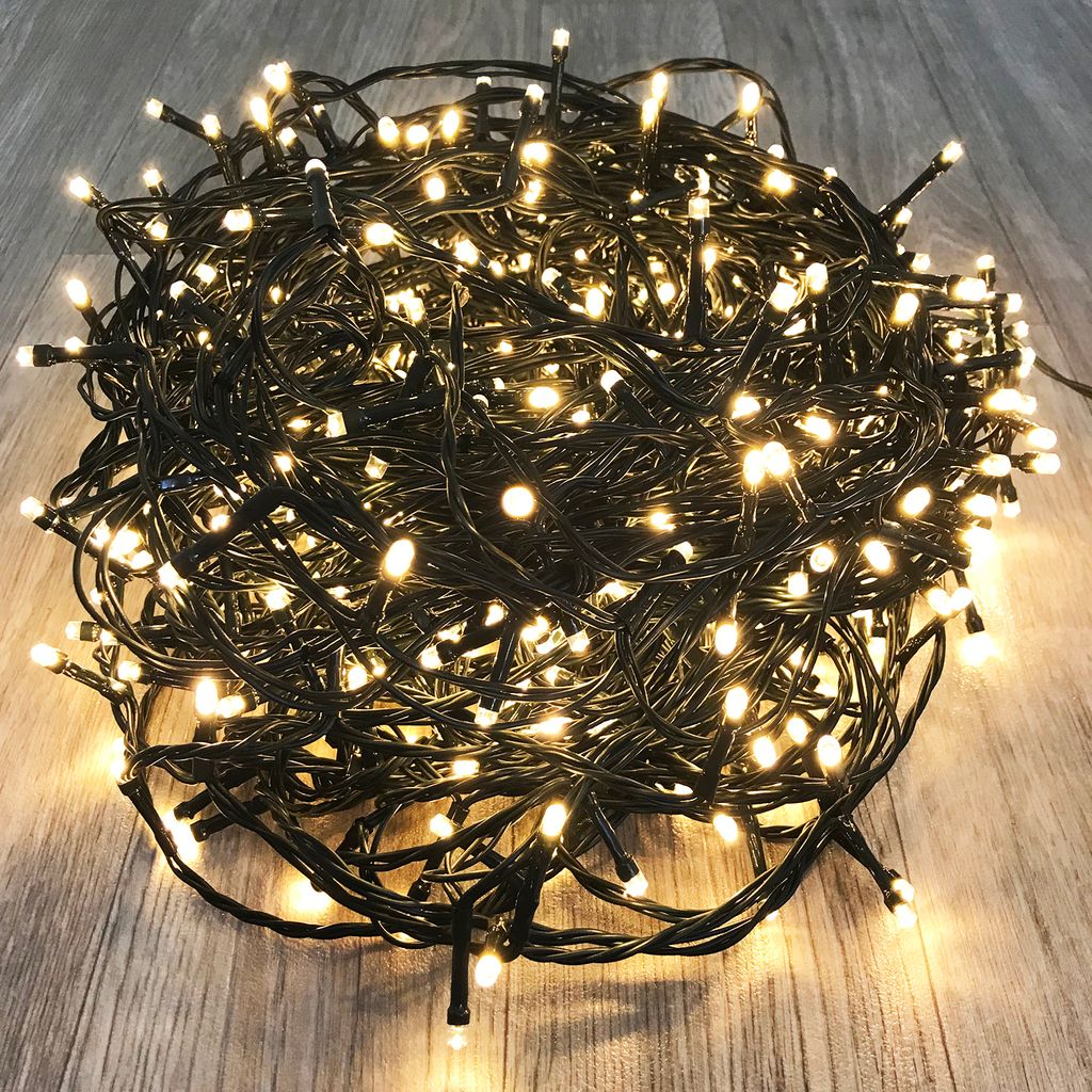 A tangled pile of warm white LED string lights on a wooden floor.