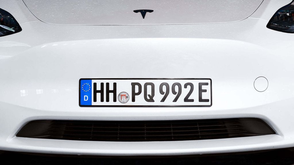 Close-up of the front of a white Tesla car, showing the license plate.