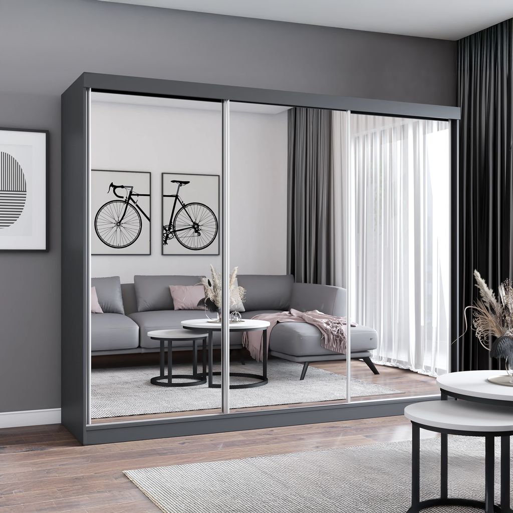 A modern living room with a large gray wardrobe with mirrored doors, a gray sectional sofa, and coffee tables.