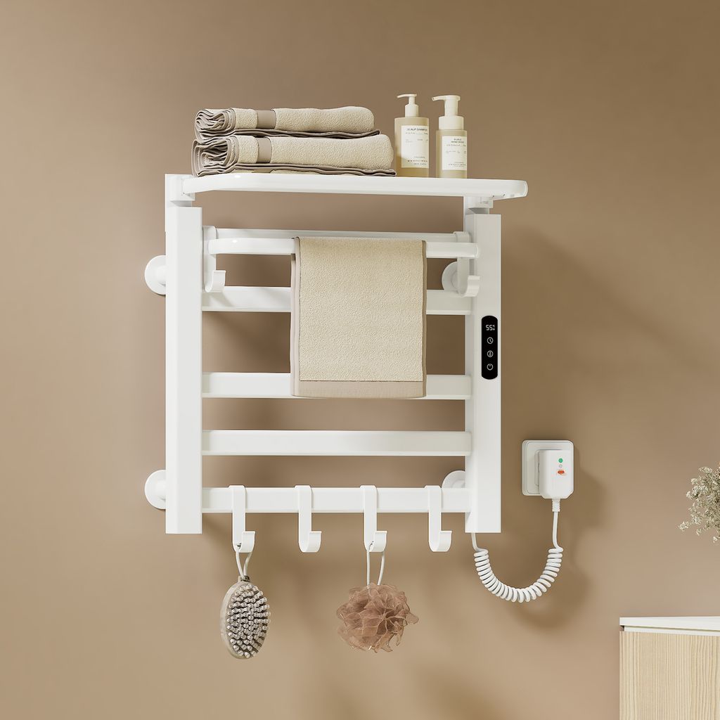 A white electric towel warmer mounted on a light brown wall, with towels, soap dispensers, and bath accessories displayed.
