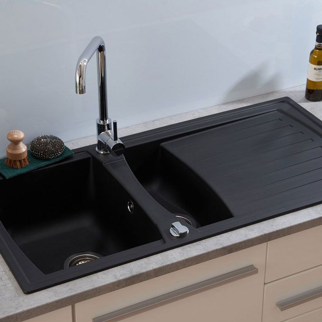 A black kitchen sink with a faucet and a drying rack.