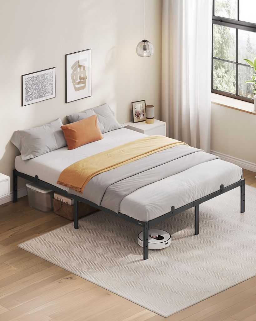 A bedroom with a bed and a robot vacuum.