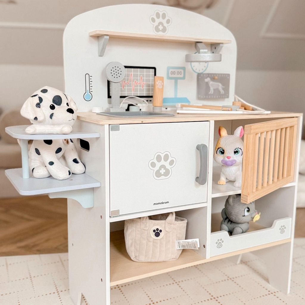 A wooden toy veterinary clinic with stuffed animals.