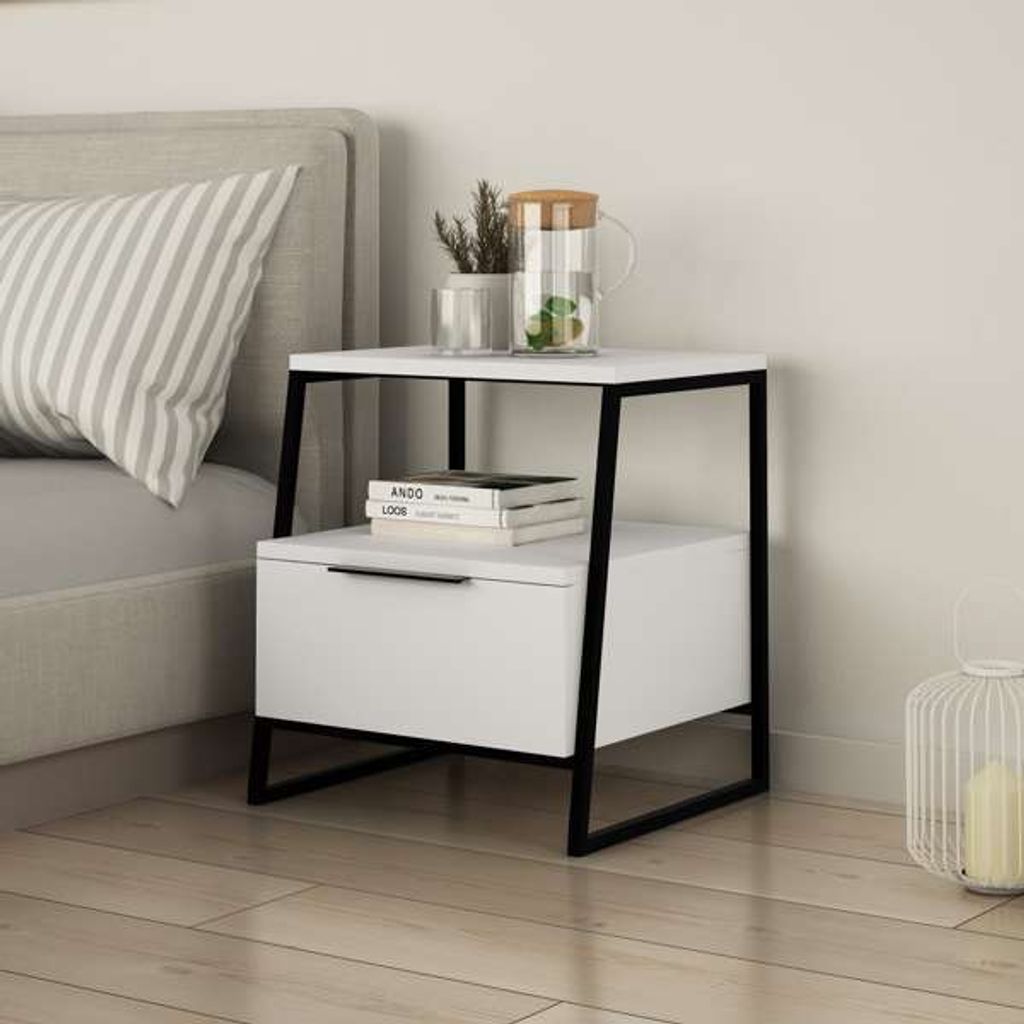 A modern white nightstand with a black frame is placed next to a bed.