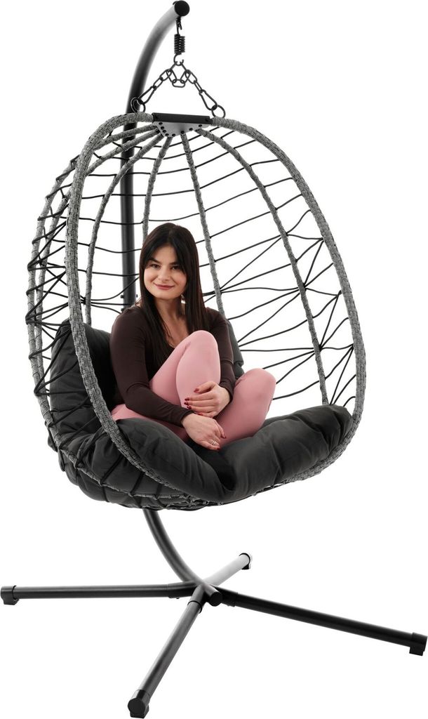 A woman sits in a hanging egg chair.
