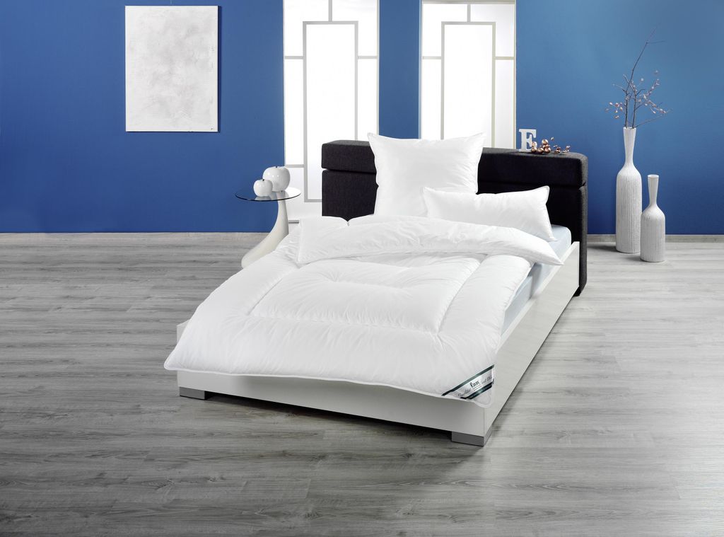 A neatly made bed with white bedding in a room with blue walls and a wooden floor.