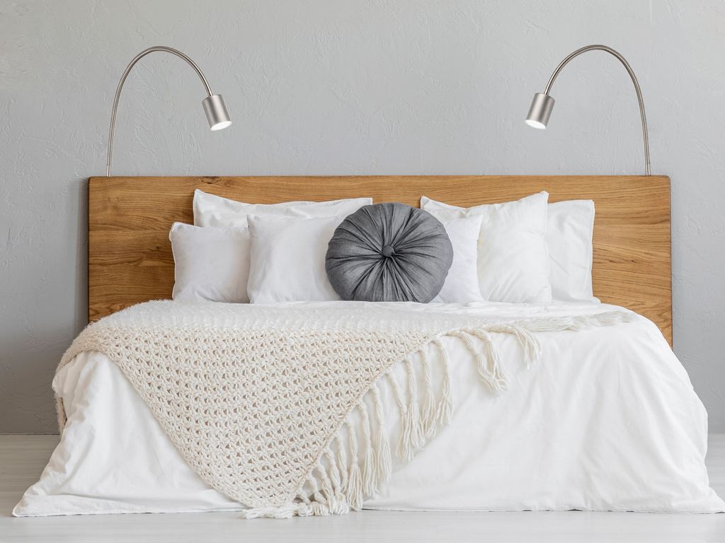 A bedroom scene with a bed, pillows, and lamps.