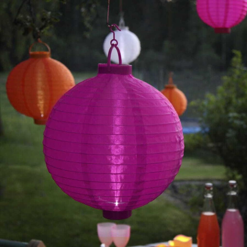 Several paper lanterns are hanging outdoors, with a table set for drinks in the foreground.
