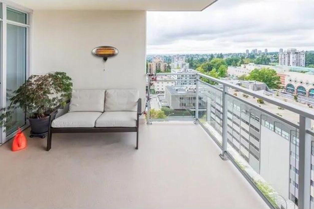 A balcony with a sofa, plant, and a view of a city.