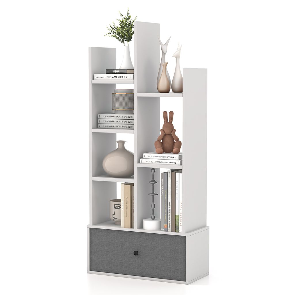 A white, multi-tiered bookshelf with a gray fabric drawer at the bottom, displaying various decorative items and books.