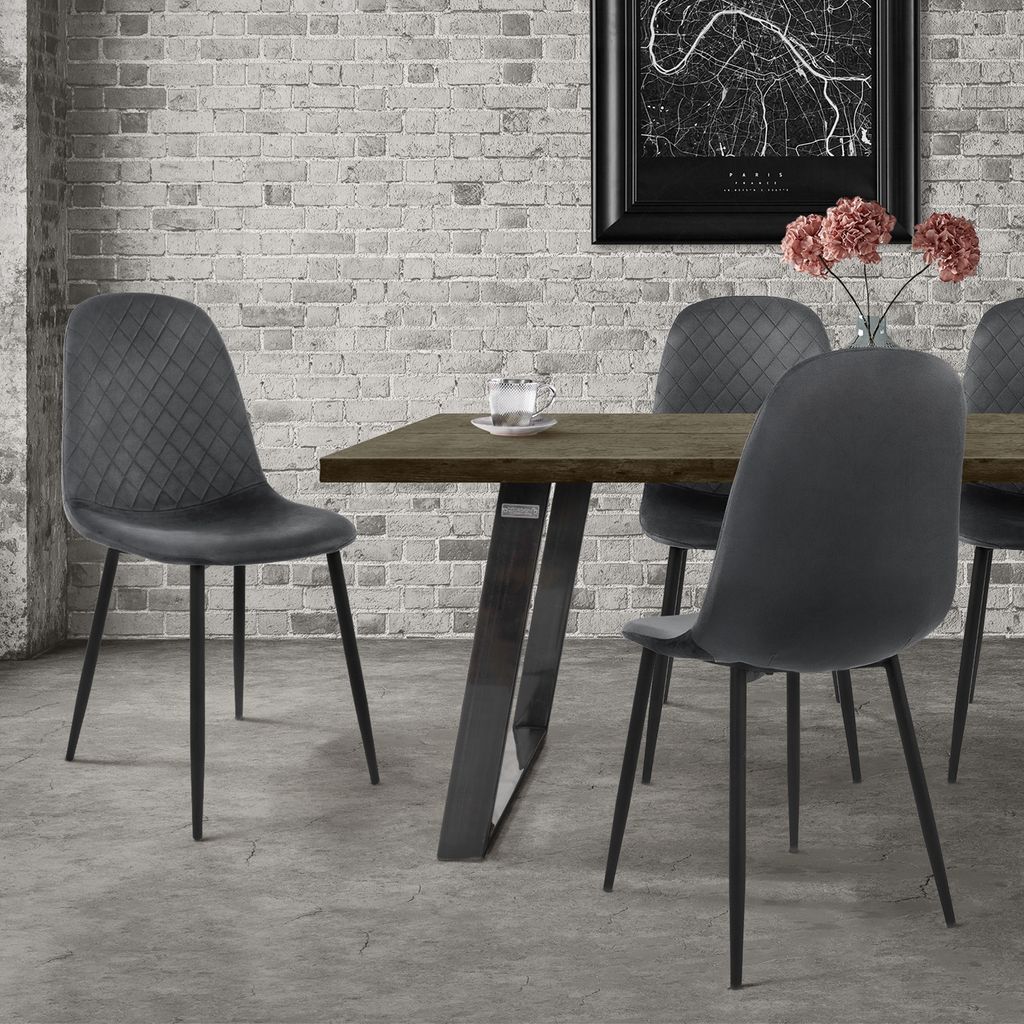 A dining set with chairs around a table, in front of a brick wall.